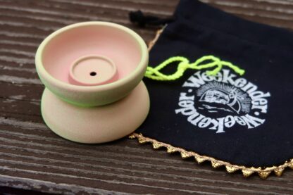 A cerakote Weekender on a wooden surface. The yo-yo has a pink look to it, but with green highlights.