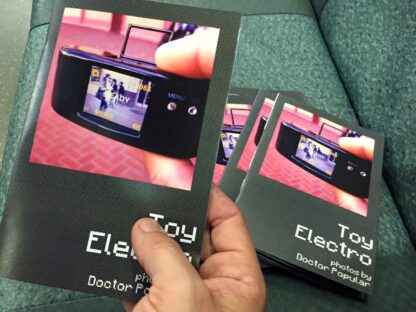 The front cover of the Toy Electro zine. On the cover of the zine is a photo of a Digital Harinezumi camera.