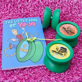 Three green yo-yos and a small comic book. The book is "The Little Book Of Yo". The yo-yos are all green Bolts, but each one has a slightly different color cap.